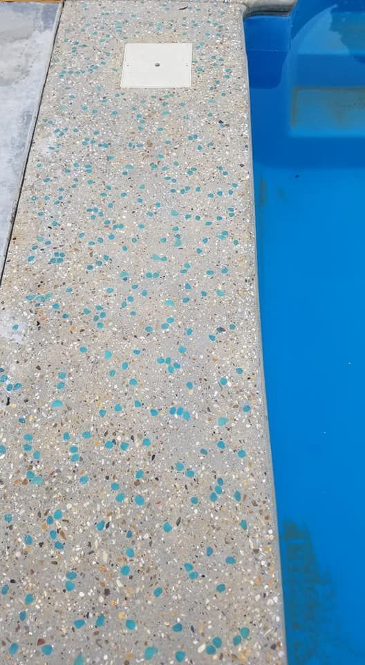 A swimming pool with a concrete deck and a blue water.