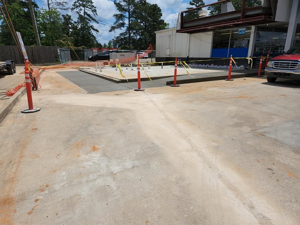 A red truck is parked in a parking lot next to a building under construction.