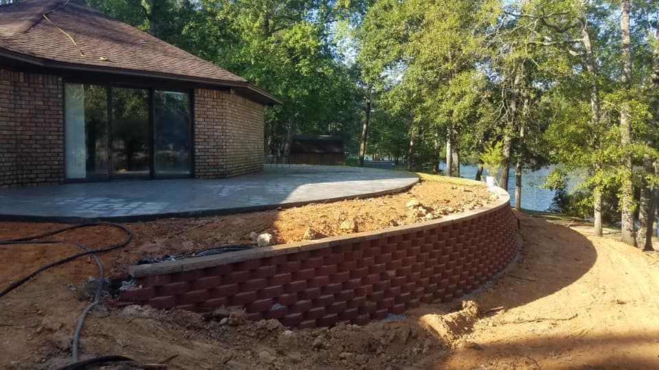 A house with a patio and a retaining wall in front of it.