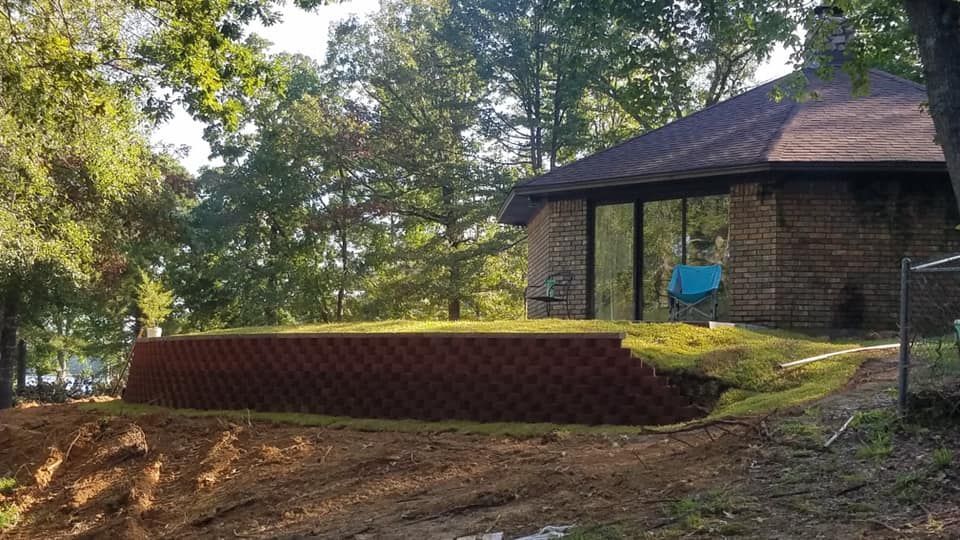 A large brick wall is being built in front of a brick house.