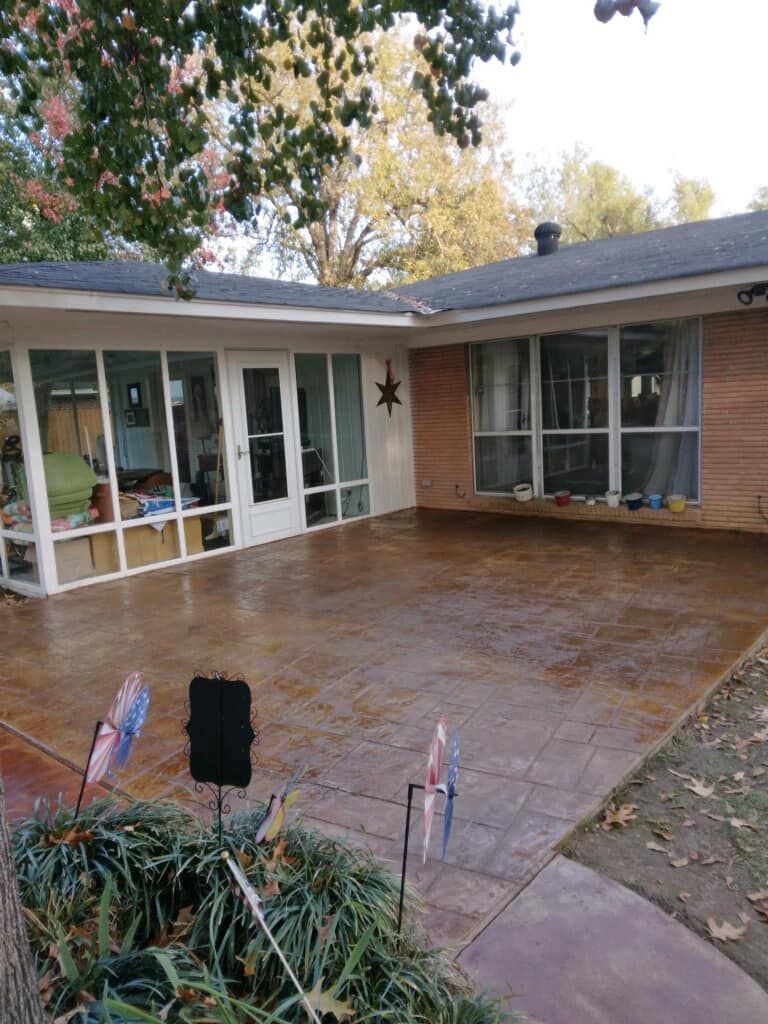A concrete patio in front of a house with a lot of windows.