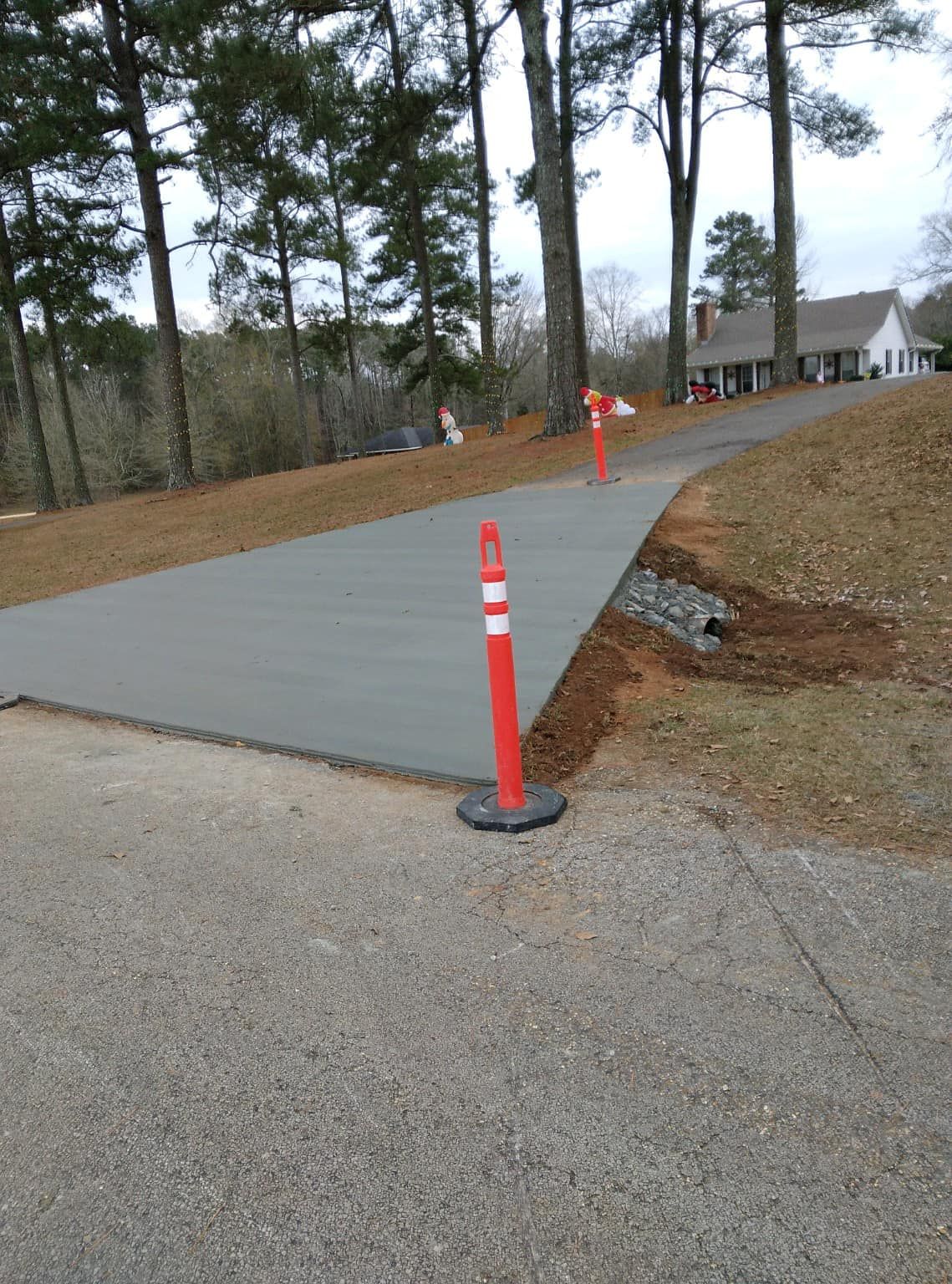 A concrete driveway with a red and white pole in the middle