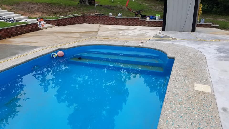 A blue swimming pool with steps and a pink ball in it.