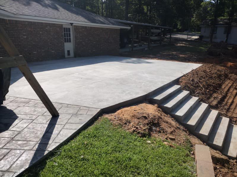 A brick house with a concrete driveway and steps leading to it