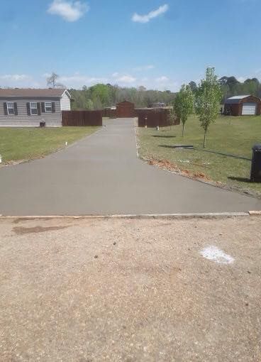 A concrete driveway leading to a house in a residential area.