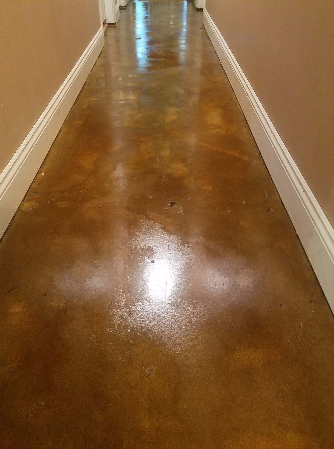 A hallway with a stained concrete floor and white trim.