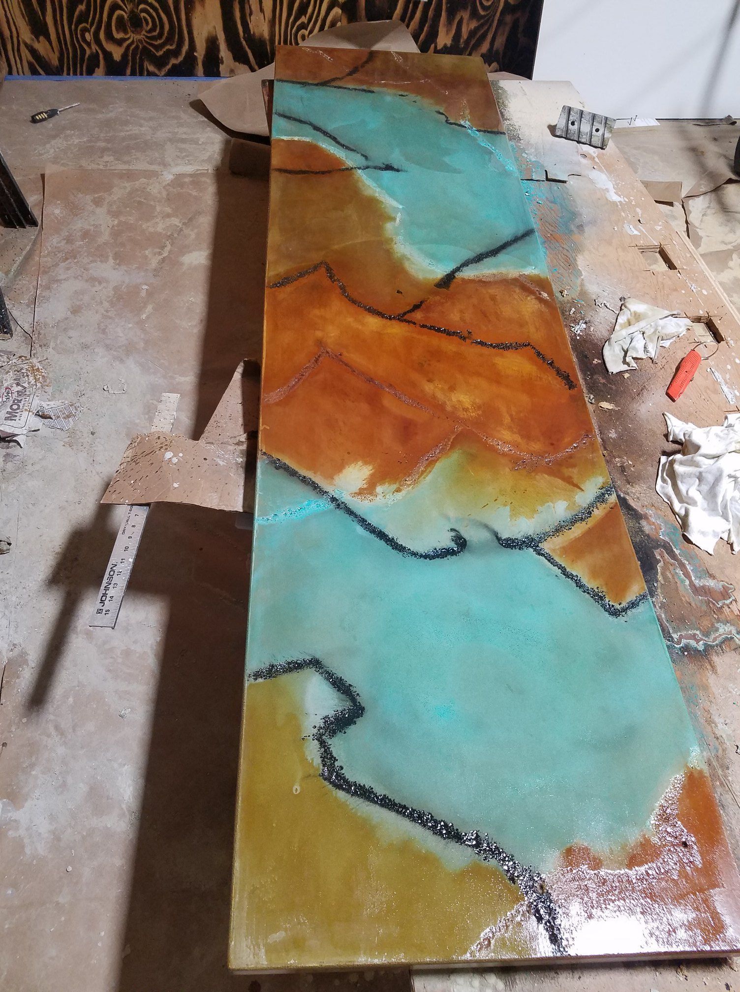 A long piece of wood with a painting on it is sitting on a table.