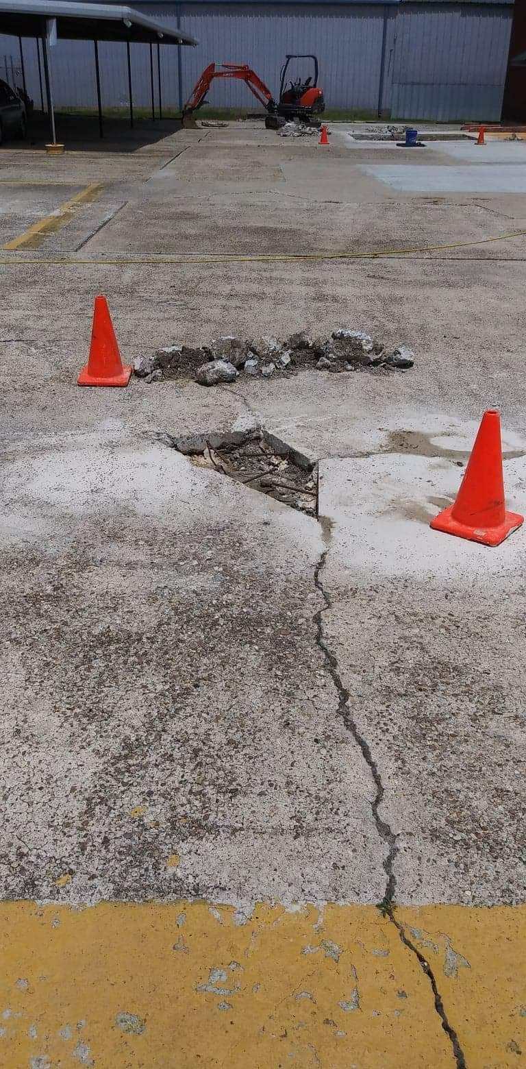Two orange traffic cones are sitting on a cracked concrete surface.