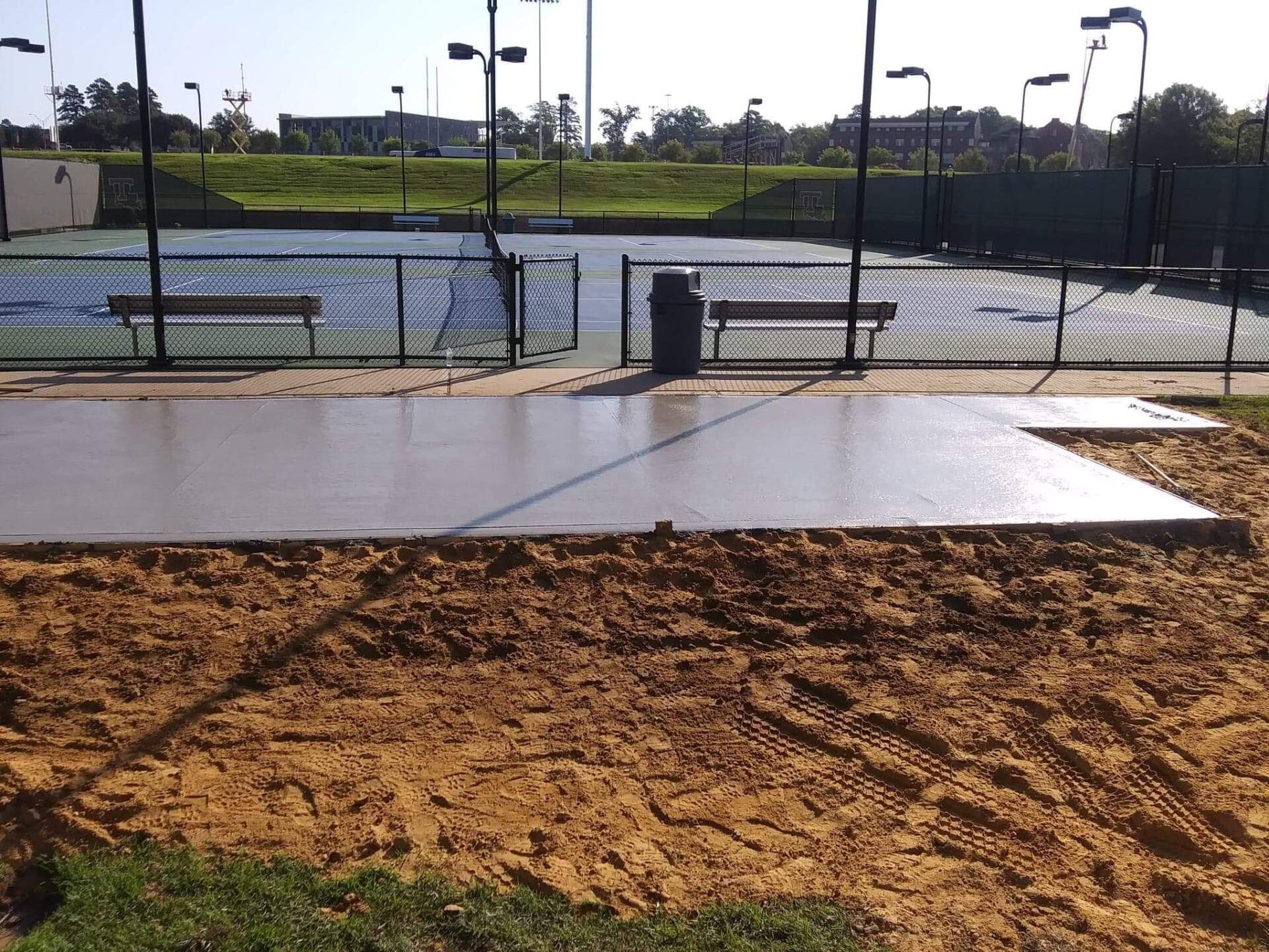 A tennis court with a concrete floor in front of it