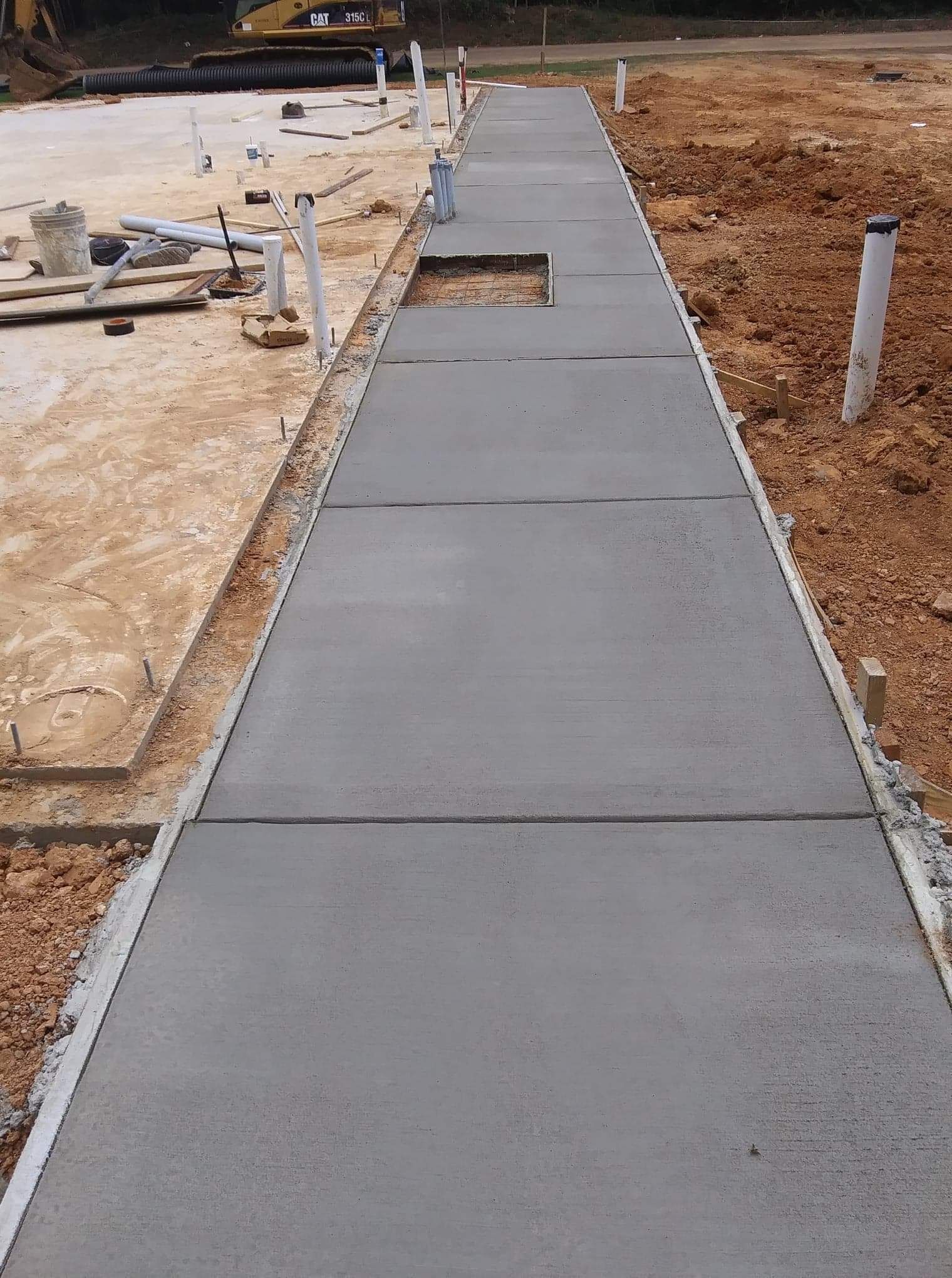 A concrete walkway is being built on a construction site.