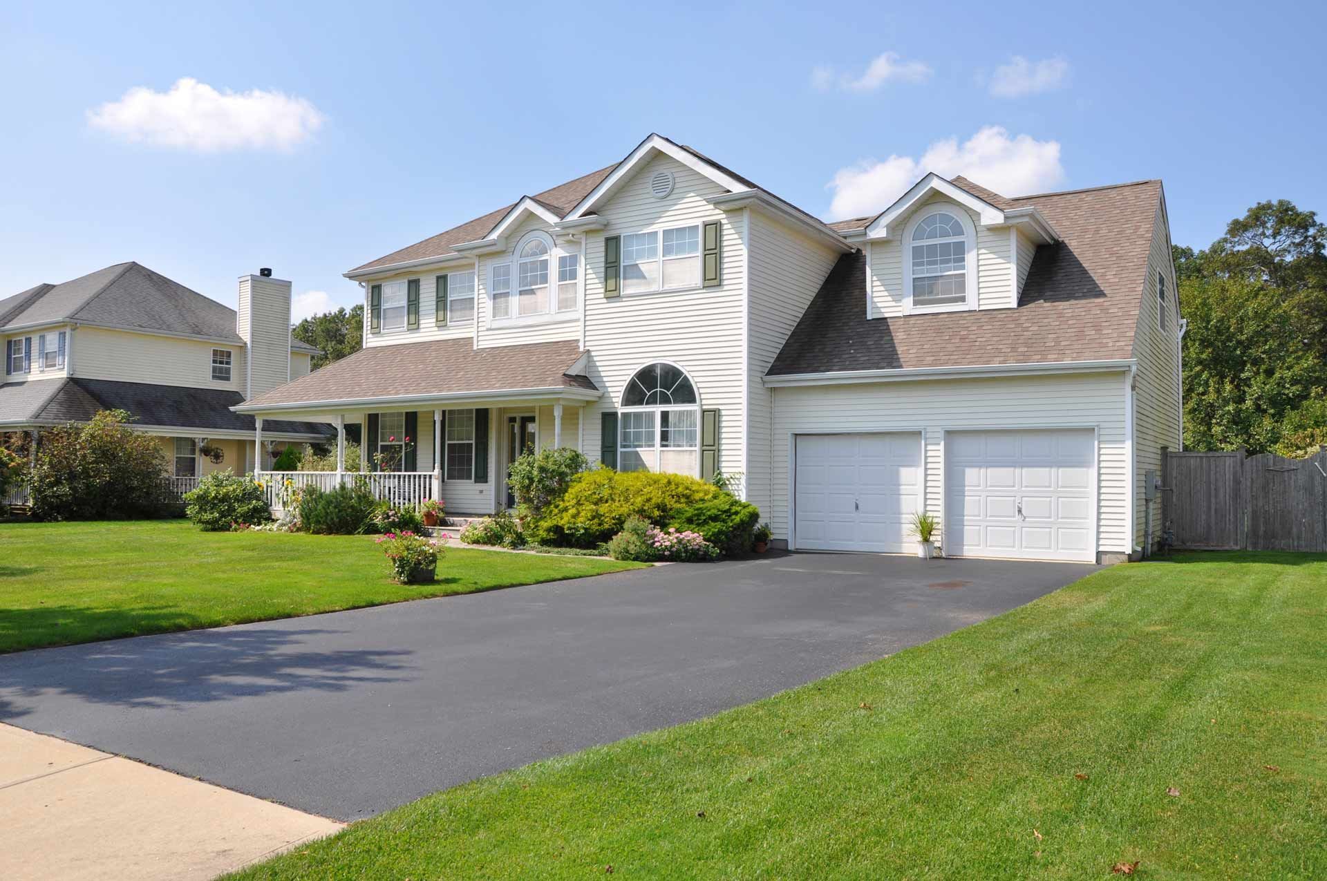 A large white house with two garage doors and a driveway