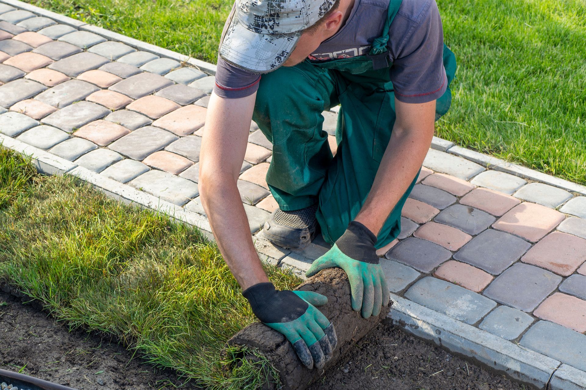 A man is laying a roll of grass in a garden