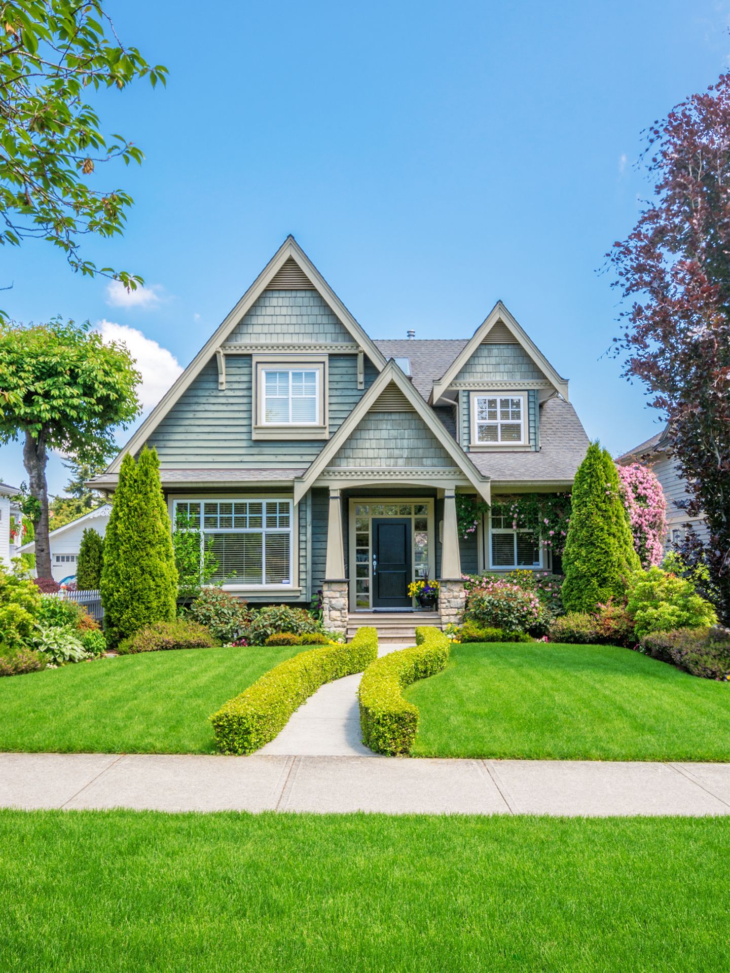 A large house with a lush green lawn and trees in front of it