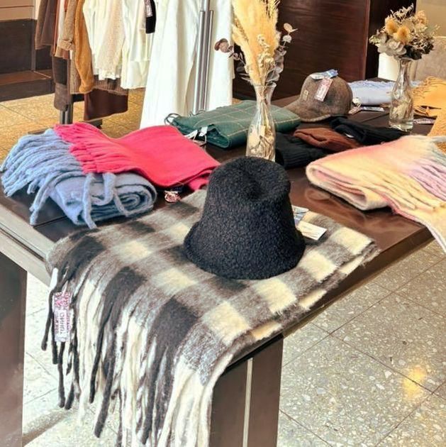 Exhibición de mesa de bufandas, sombreros y ropa en una tienda minorista.