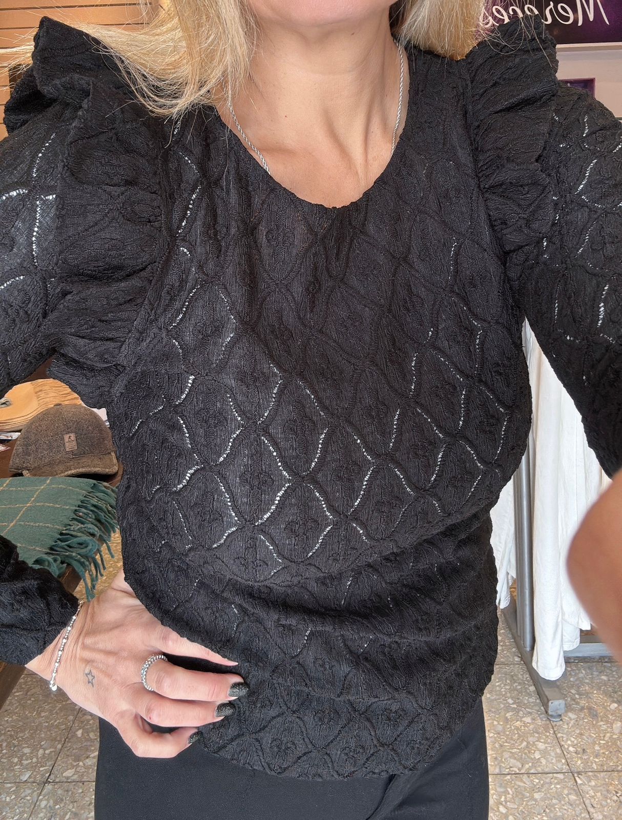 Mujer con suéter negro texturizado y mangas abullonadas.