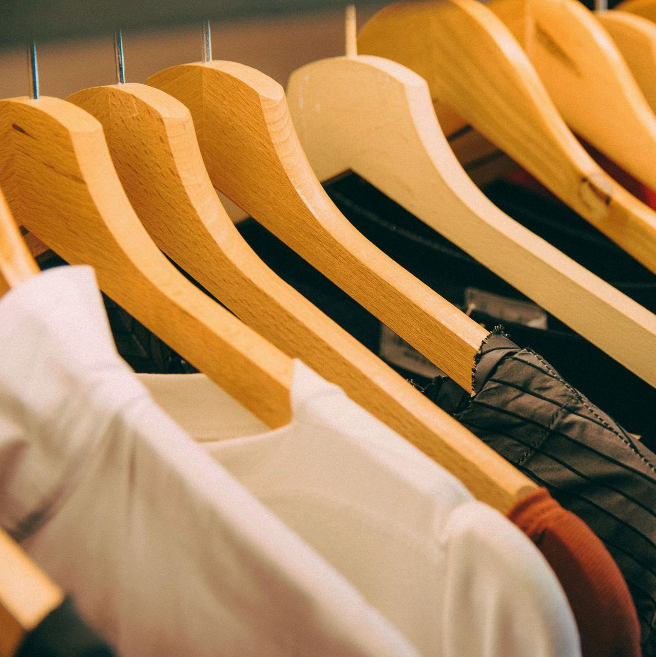 Perchas de madera que sostienen diversas prendas de vestir en un armario.