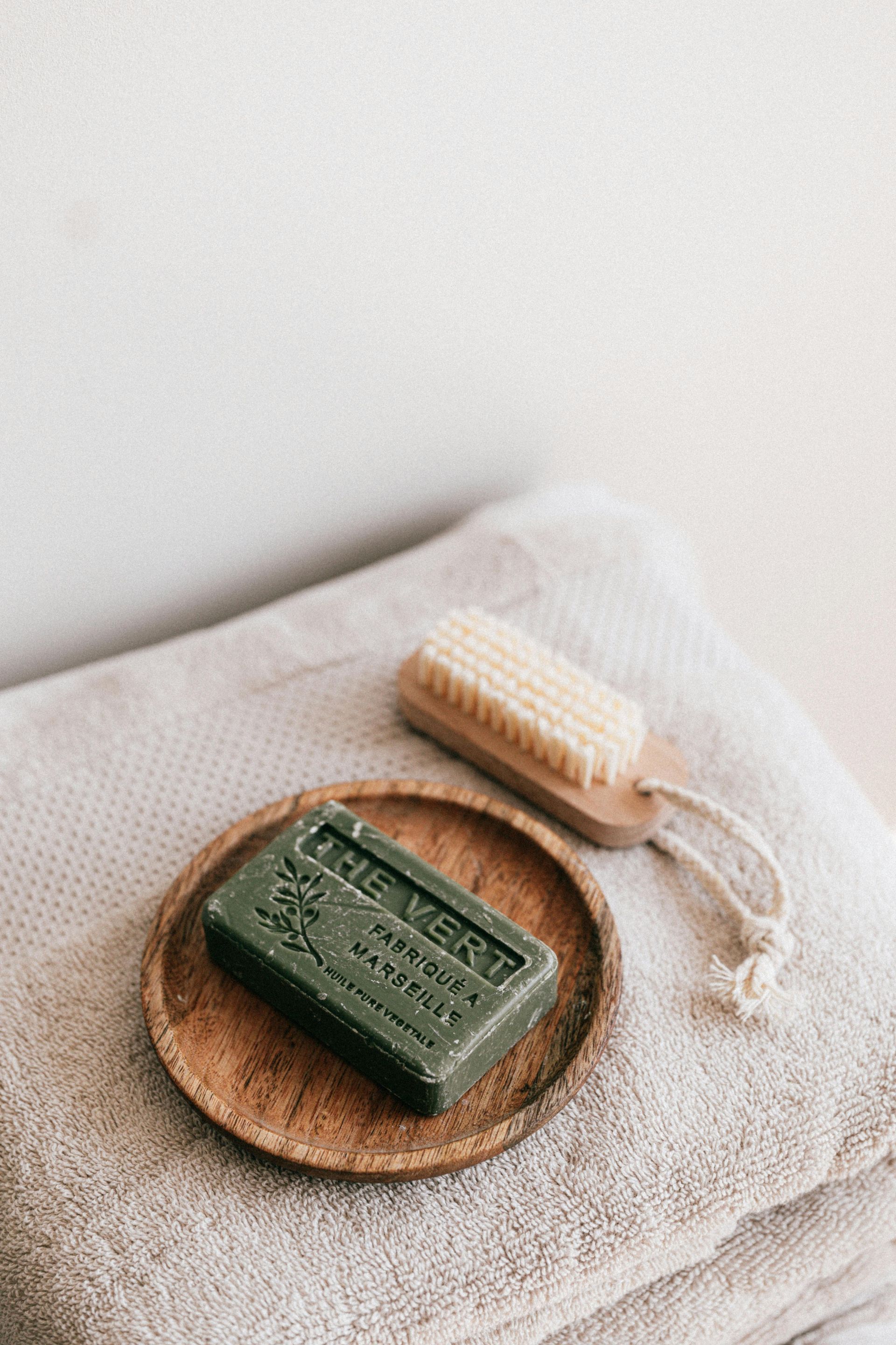 A bar of soap is sitting on a wooden plate on top of a stack of towels.