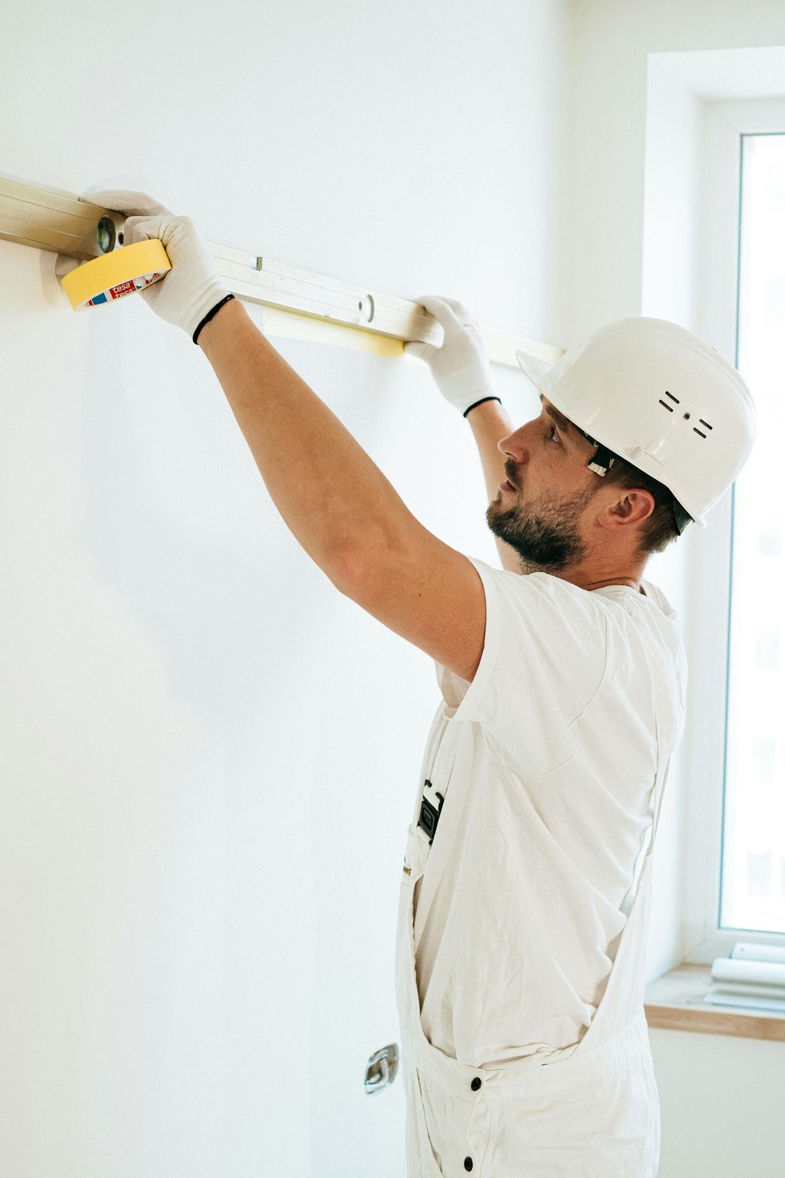 A man is measuring a wall with a tape measure.