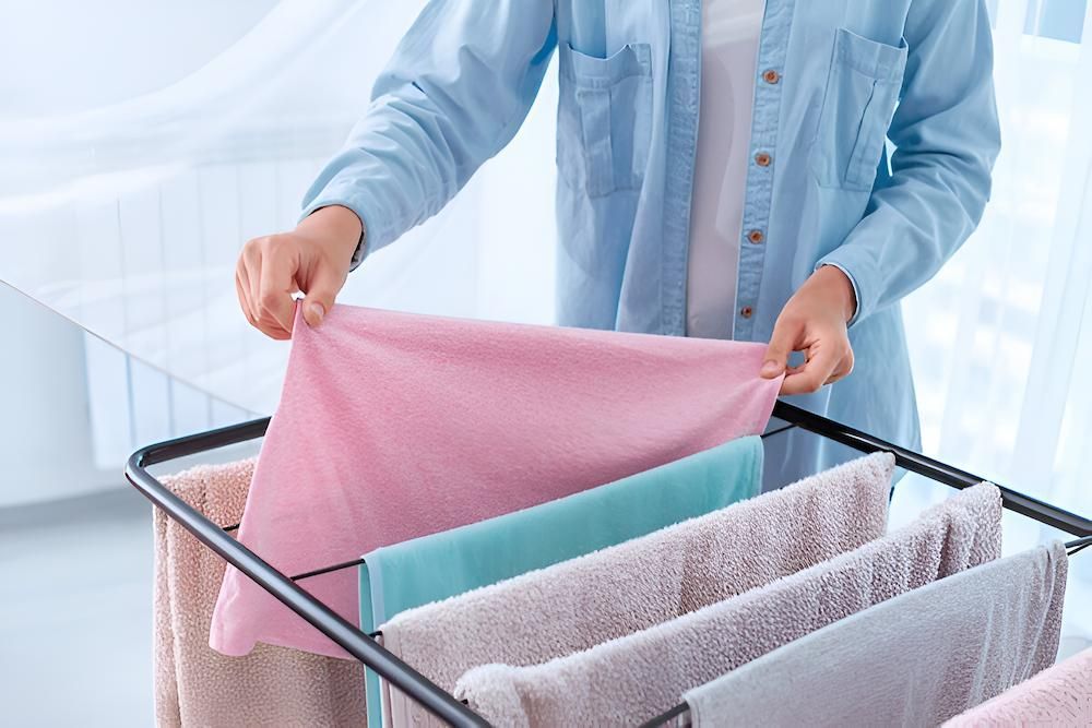 A Woman is Hanging Towels on a Drying Rack — South Coast Clothes Lines in Dapto, NSW