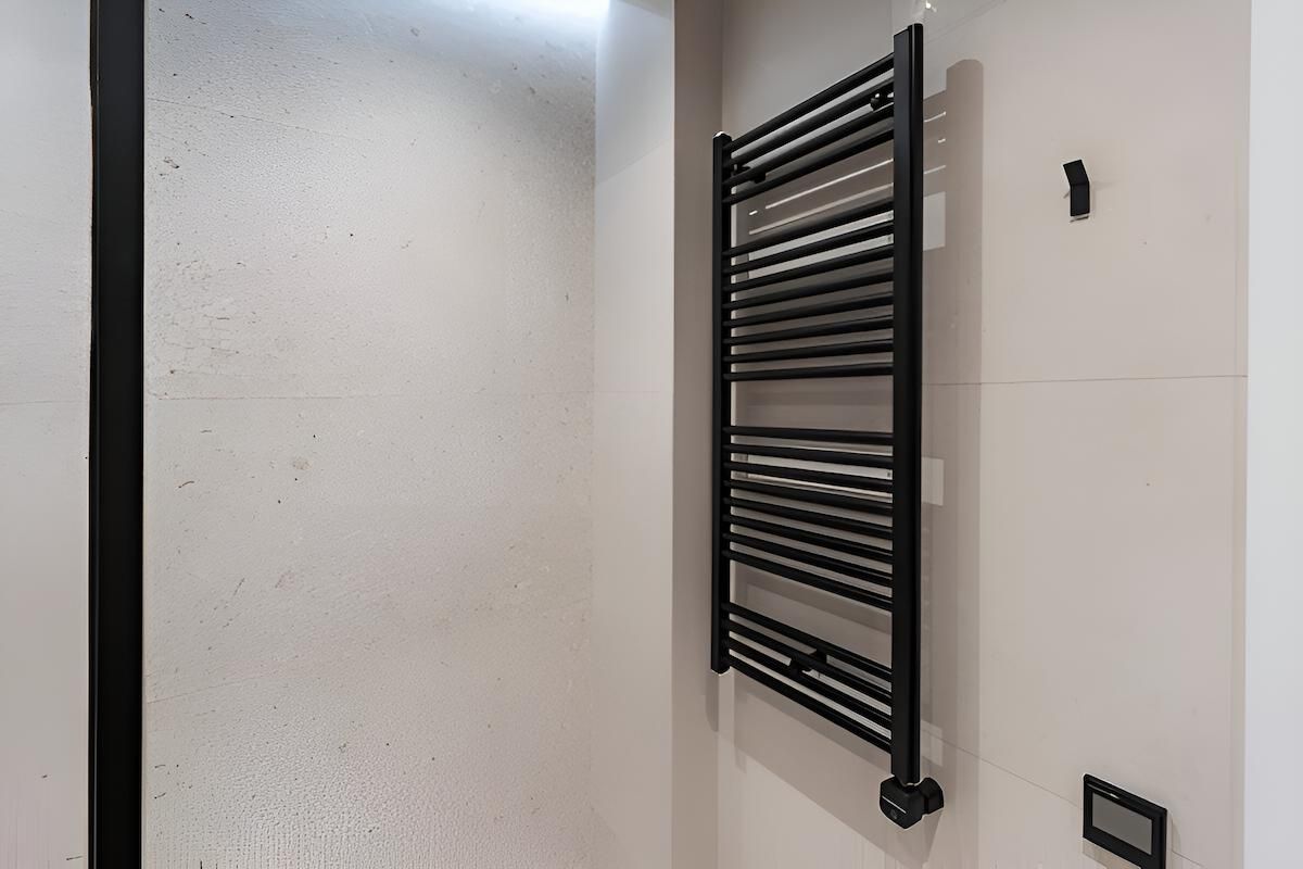 A Black Towel Rack is Hanging on a White Wall in a Bathroom — South Coast Clothes Lines in Dapto, NSW
