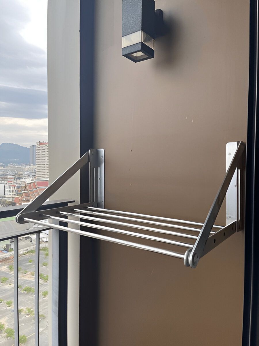 A Clothes Drying Rack is Attached to a Wall on a Balcony — South Coast Clothes Lines in Thirroul, NSW