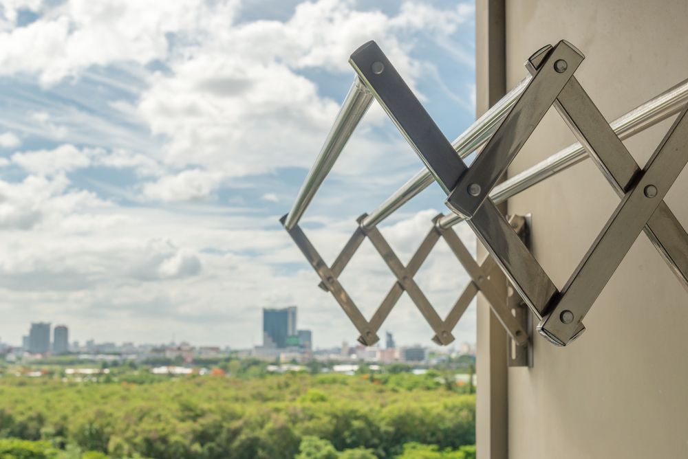 A Clothes Drying Rack is Hanging on a Wall Next to a Window — South Coast Clothes Lines in Dapto, NSW