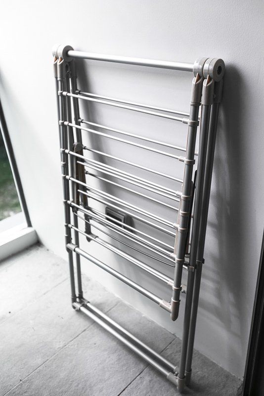 A Clothes Drying Rack is Sitting on a Tiled Floor Next to a Window — South Coast Clothes Lines in Shellharbour, NSW