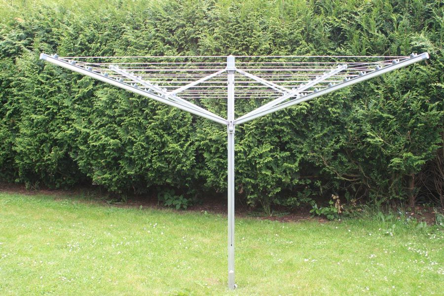 A Clothes Line is Sitting in the Grass in Front of a Hedge — South Coast Clothes Lines in Shellharbour, NSW