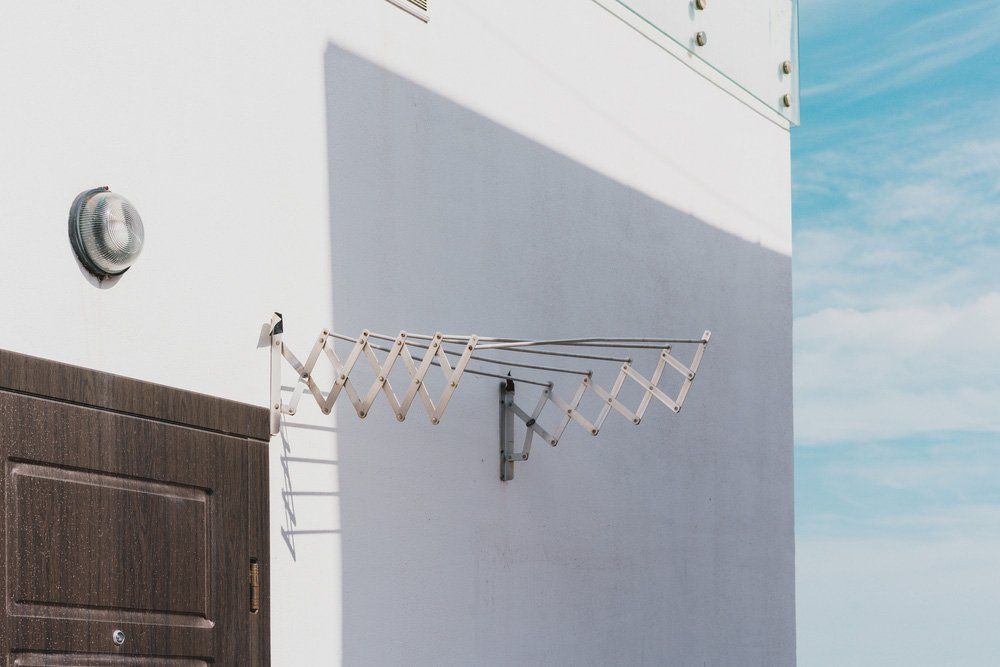 A Clothes Line is Hanging on the Side of a Building Next to a Door — South Coast Clothes Lines in Shellharbour, NSW