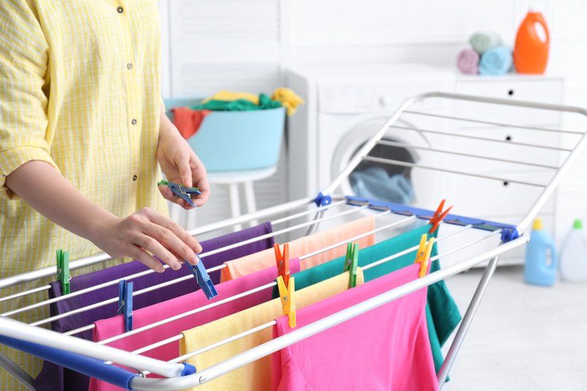 A Woman is Hanging Clothes on a Drying Rack in a Laundry Room — South Coast Clothes Lines in Southern Highlands, NSW