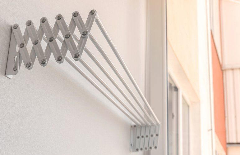A White Clothes Drying Rack is Hanging on a White Wall — South Coast Clothes Lines in Nowra, NSW