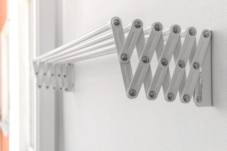 A White Clothes Drying Rack is Hanging on a White Wall — South Coast Clothes Lines in Thirroul, NSW