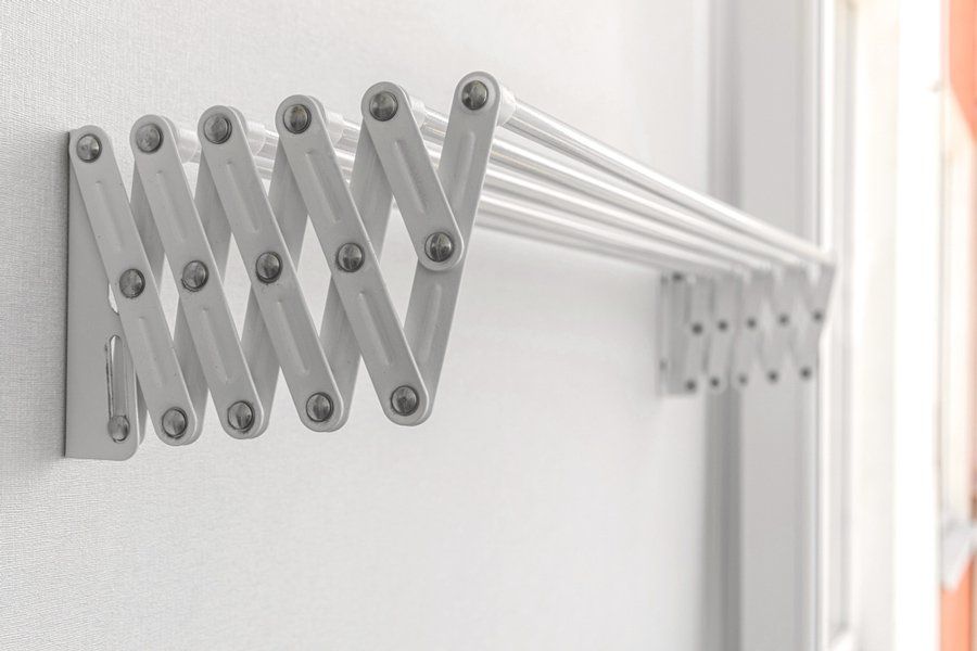 A White Clothes Drying Rack is Hanging on a White Wall — South Coast Clothes Lines in Wollongong, NSW