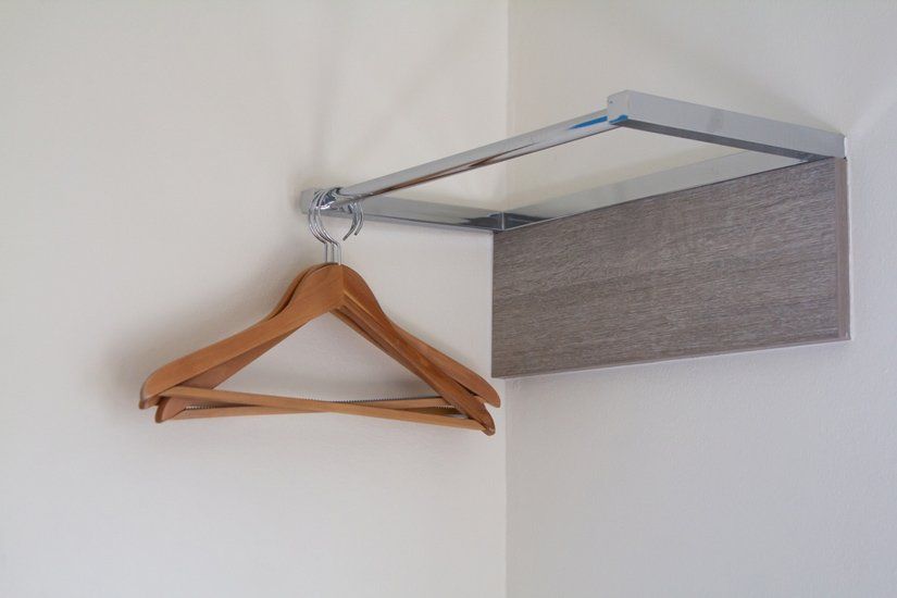 A Pair of Wooden Hangers Hanging on a Wall Next to a Shelf — South Coast Clothes Lines in Wollongong, NSW