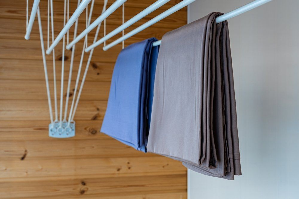 Clothes Are Hanging on a Clothes Line Against a Wooden Wall — South Coast Clothes Lines in Nowra, NSW
