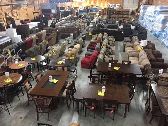 A large warehouse filled with furniture including tables and chairs