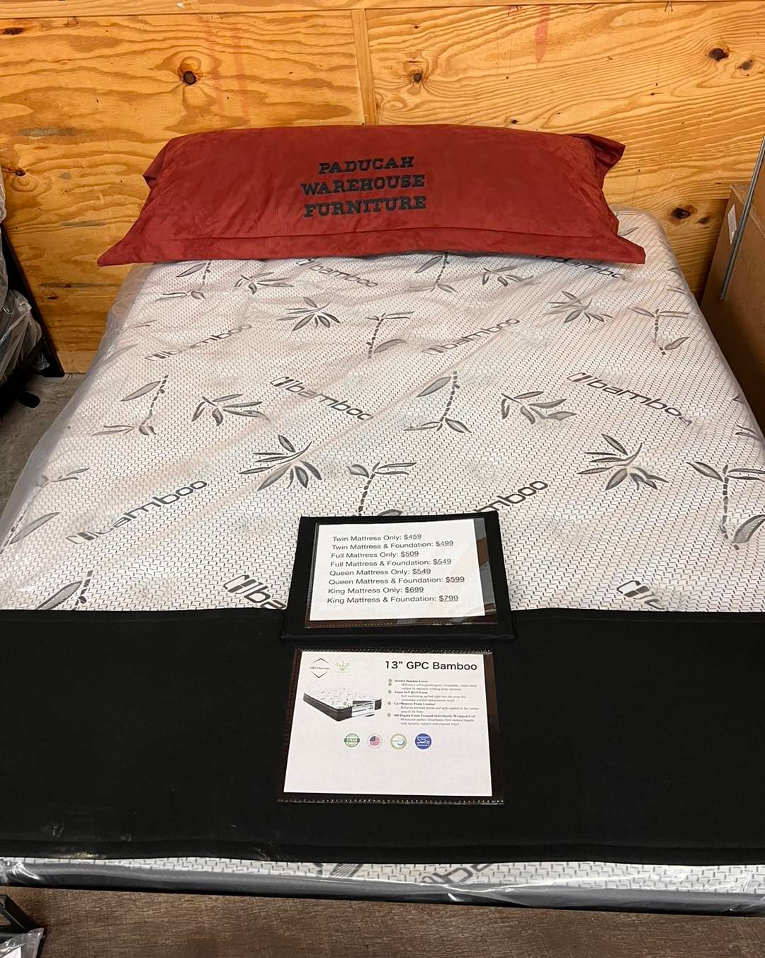 A bed with a red pillow on top of it in a warehouse.