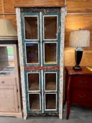 A blue and white cabinet with glass doors is sitting next to a lamp.