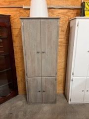 A gray cabinet is sitting next to a white cabinet in a room.