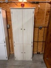 A white cabinet with a lamp on top of it in a room.