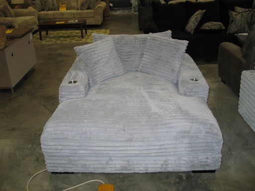 A large white chair is sitting on a concrete floor in a living room.