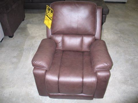 A brown leather recliner is sitting on a carpet in a living room.