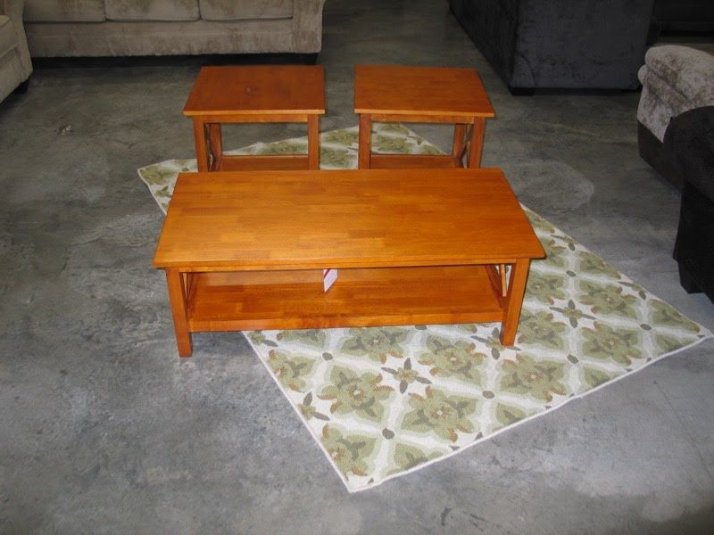 Three wooden coffee tables on a rug in a living room