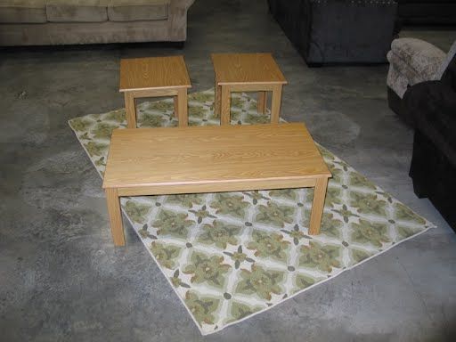 Three wooden tables are sitting on a rug in a living room.