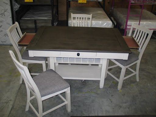 A table and chairs are sitting on a concrete floor in a warehouse.