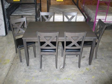 A dining table and chairs are sitting on a concrete floor in a warehouse.