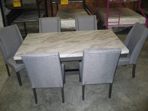 A marble dining table with gray chairs in a warehouse.