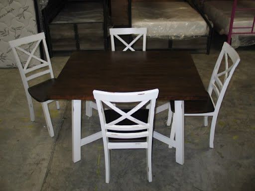 A wooden table with four white chairs on it