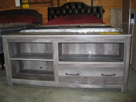 A wooden shelf with drawers and shelves next to a bed.