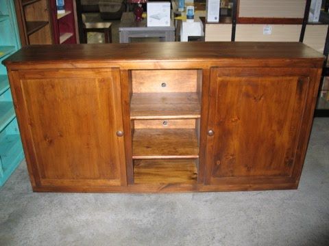 A wooden cabinet with two doors and shelves is sitting on a concrete floor.